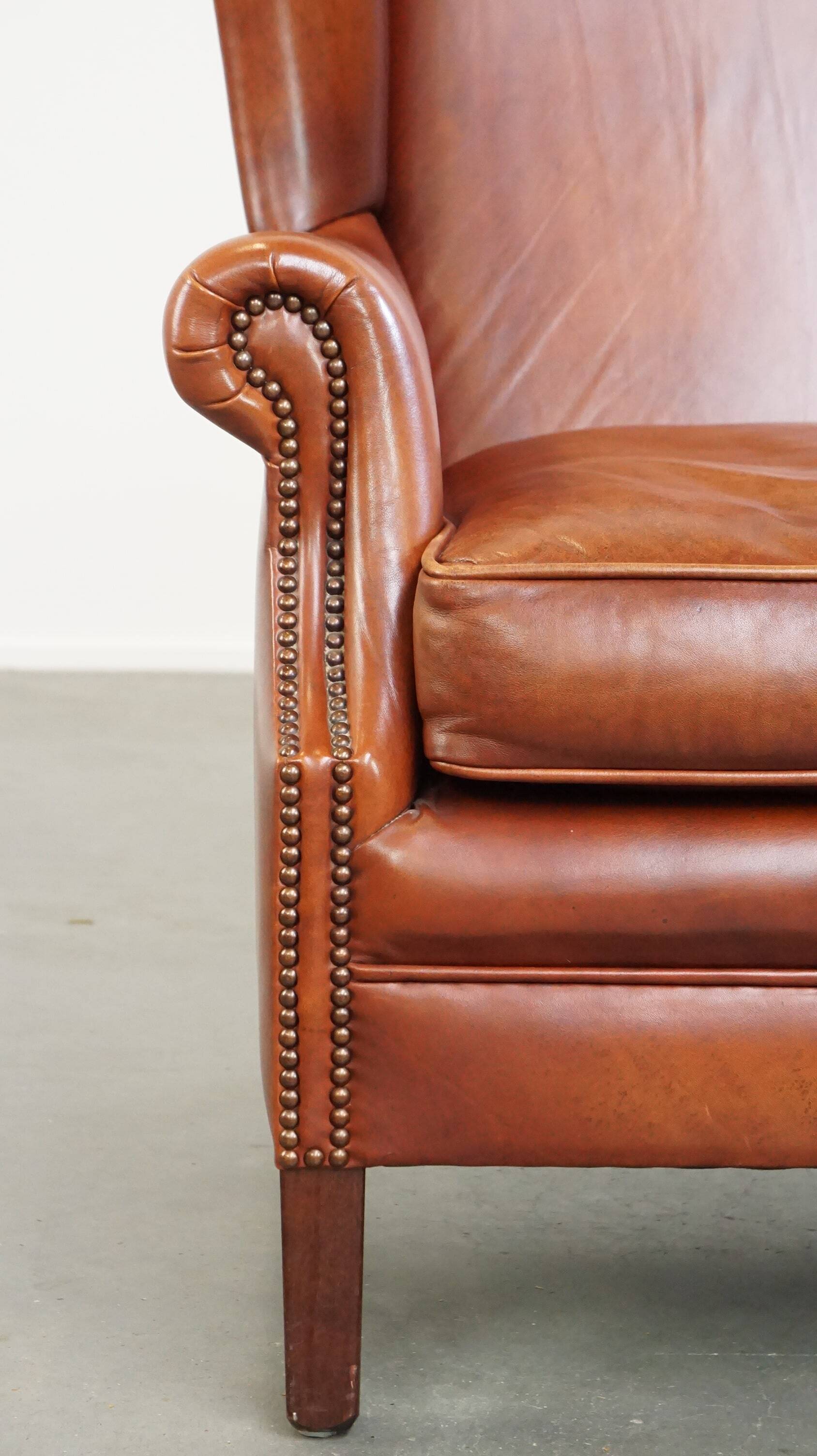 Fauteuil en cuir confortable et bien entretenu, fini avec des clous décoratifs de style anglais