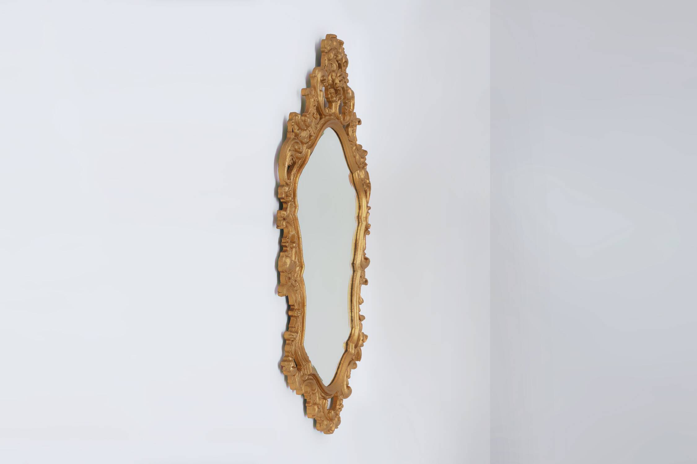 French Rococo or Baroque style facet-cut crest mirror in gilded carved wood