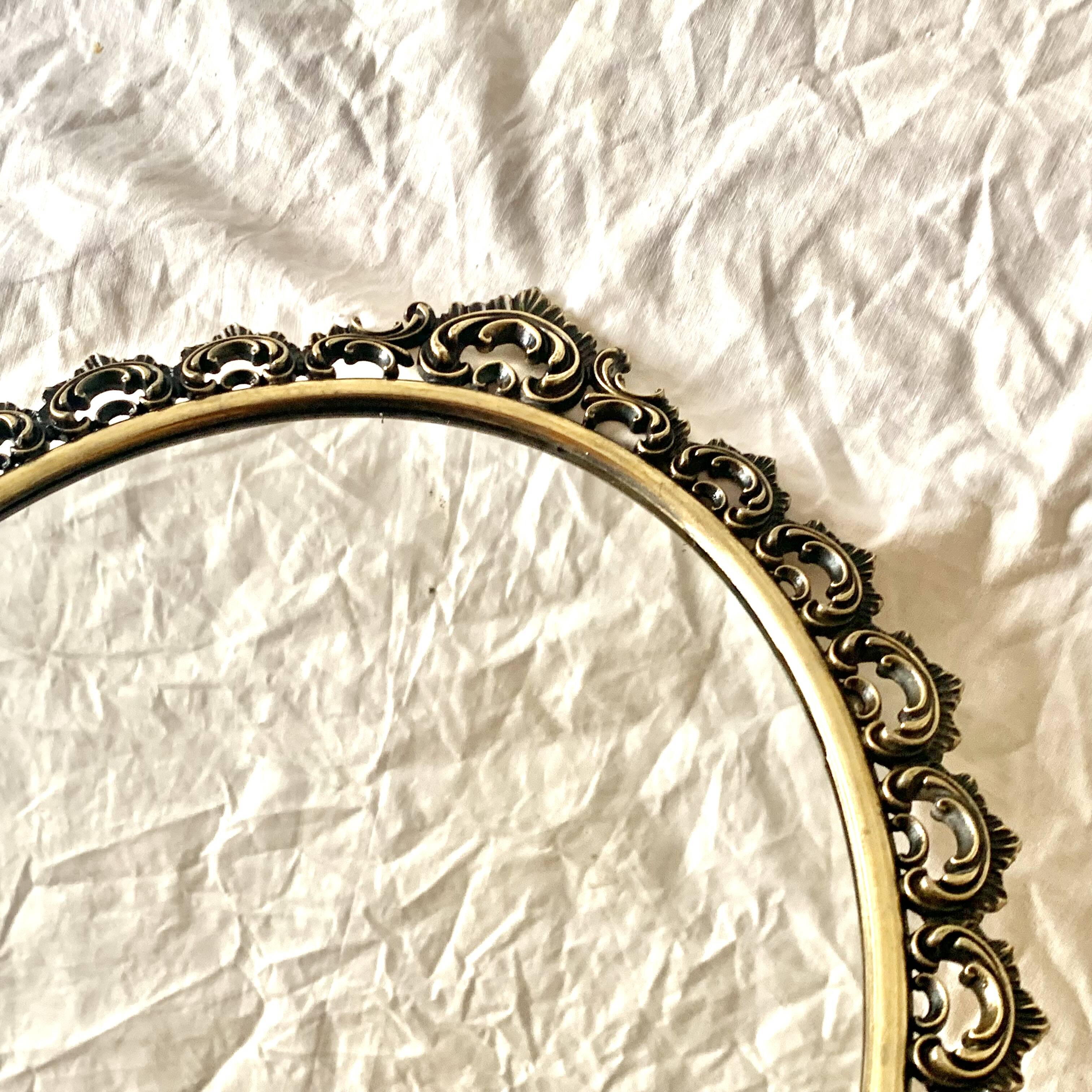 Old oval wall mirror in gilded brass