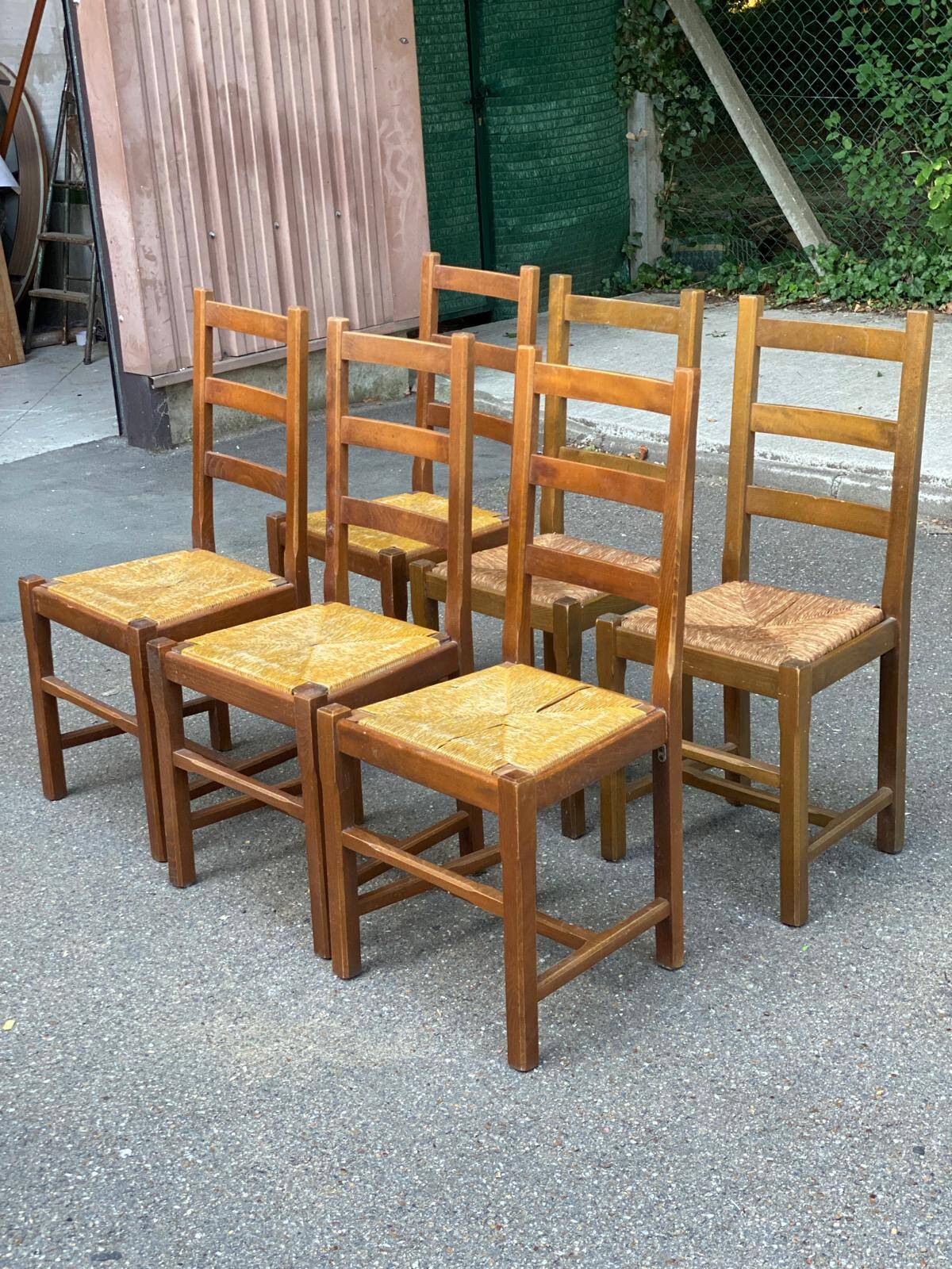 6 light solid wood chairs with high straw backs, farmhouse style.