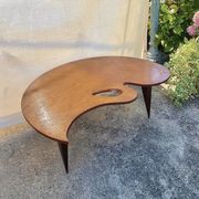 Mid-century coffee table with a palette shape and splayed legs.