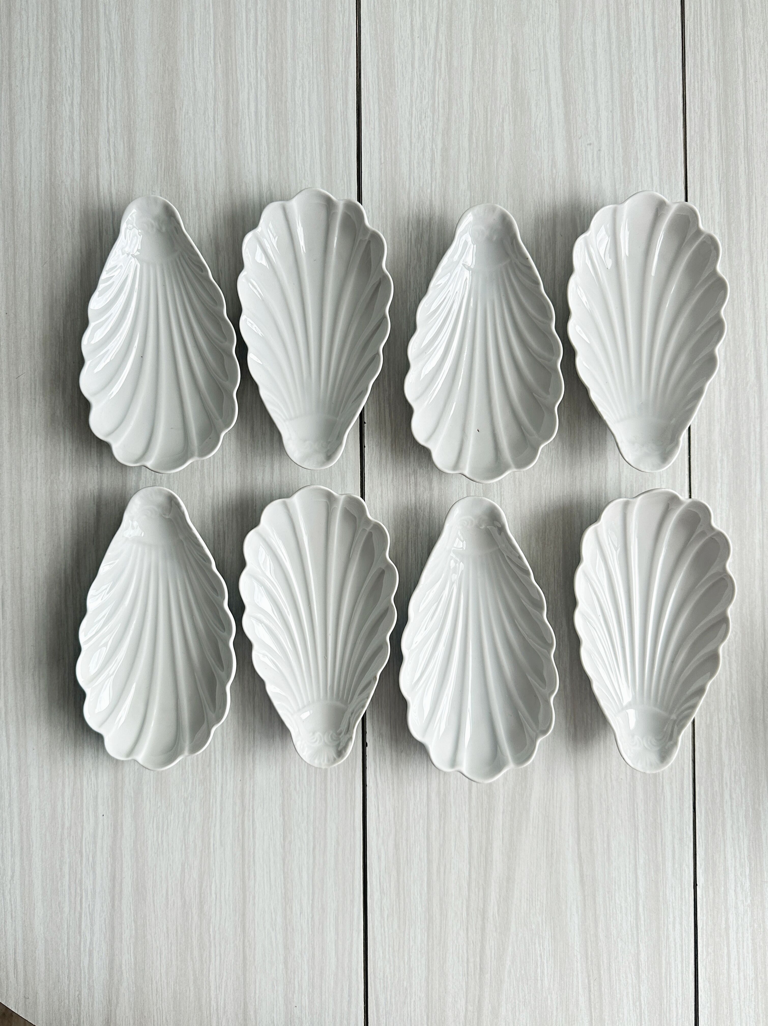 Set of white porcelain ramekins, ribbed shell shape.