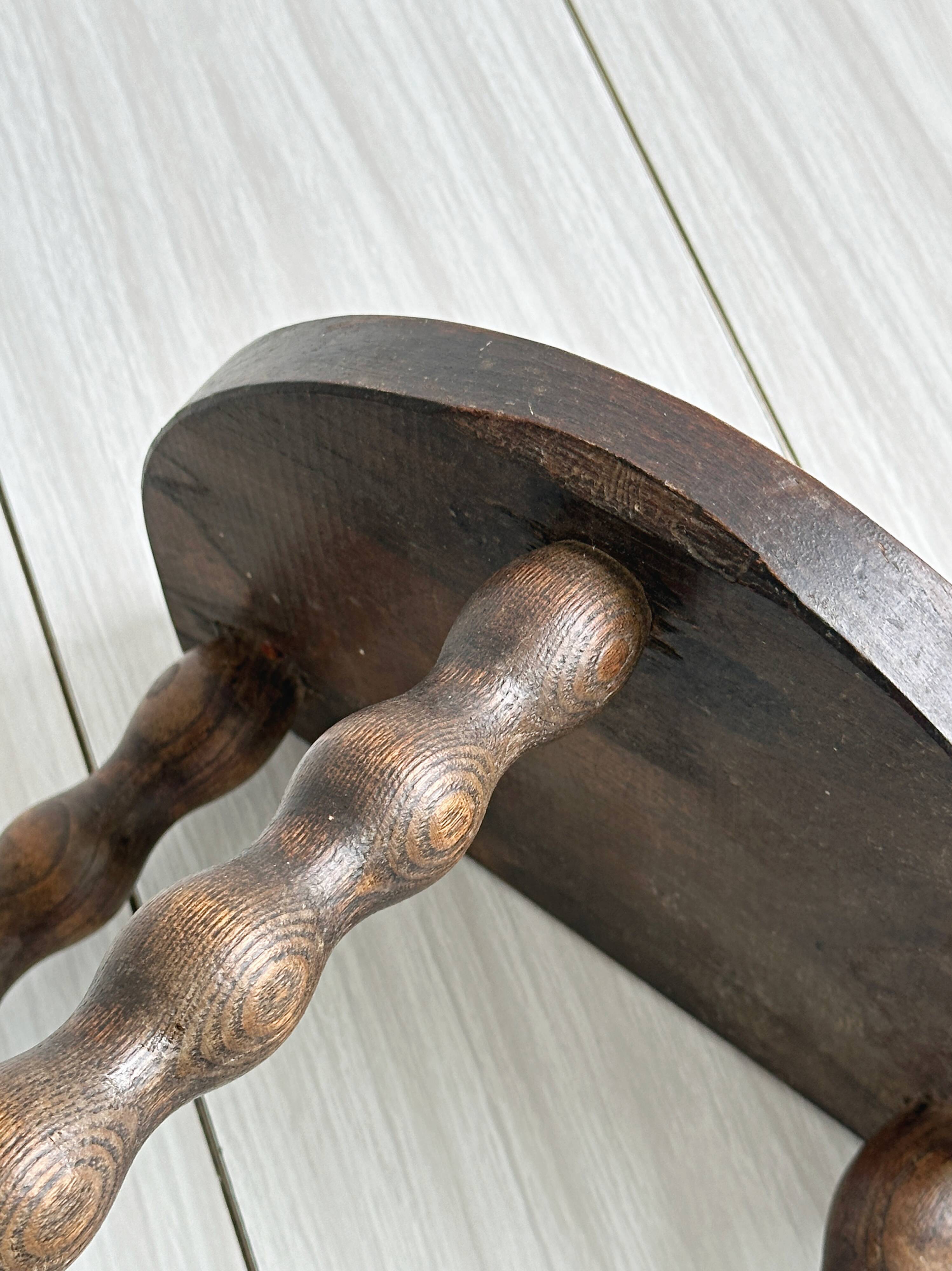 Three-legged demi-lune stool made of turned wood
