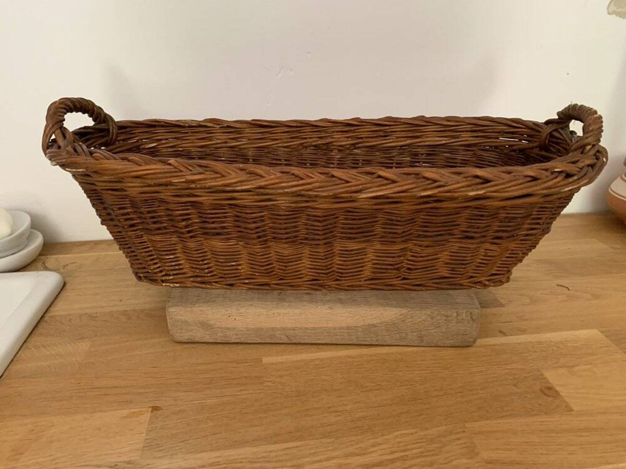 Vintage brown wicker baguette basket, elongated shape, with integrated handles.