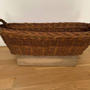 Vintage brown wicker baguette basket, elongated shape, with integrated handles.