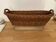 Vintage brown wicker baguette basket, elongated shape, with integrated handles.
