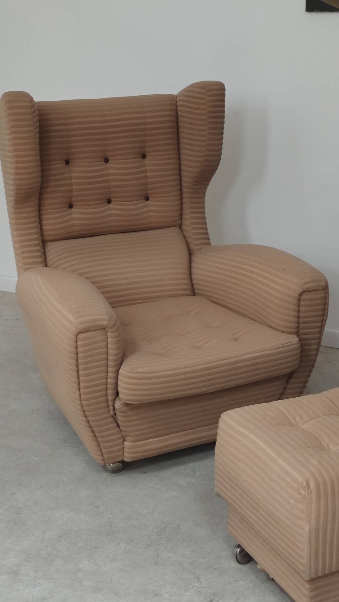 Beige wingback armchair and TVAR footrest, former Czechoslovakia.
