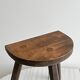 Antique wooden tripod stool with a semi-circular seat.