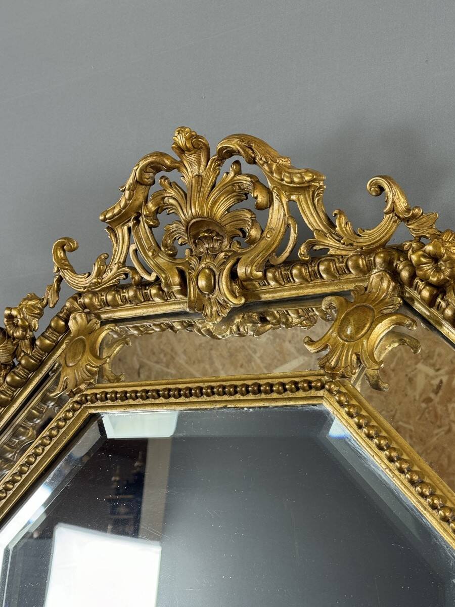 Antique octagonal mirror in richly carved gilded wood, Louis XV style.