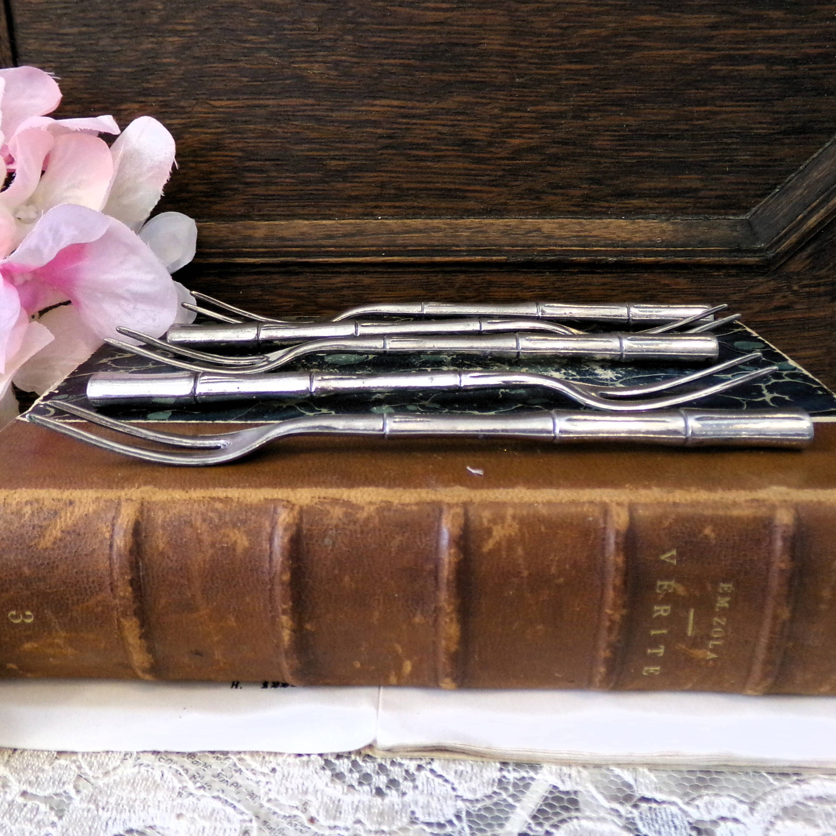 Five silver-plated metal appetizer forks with bamboo-style handles