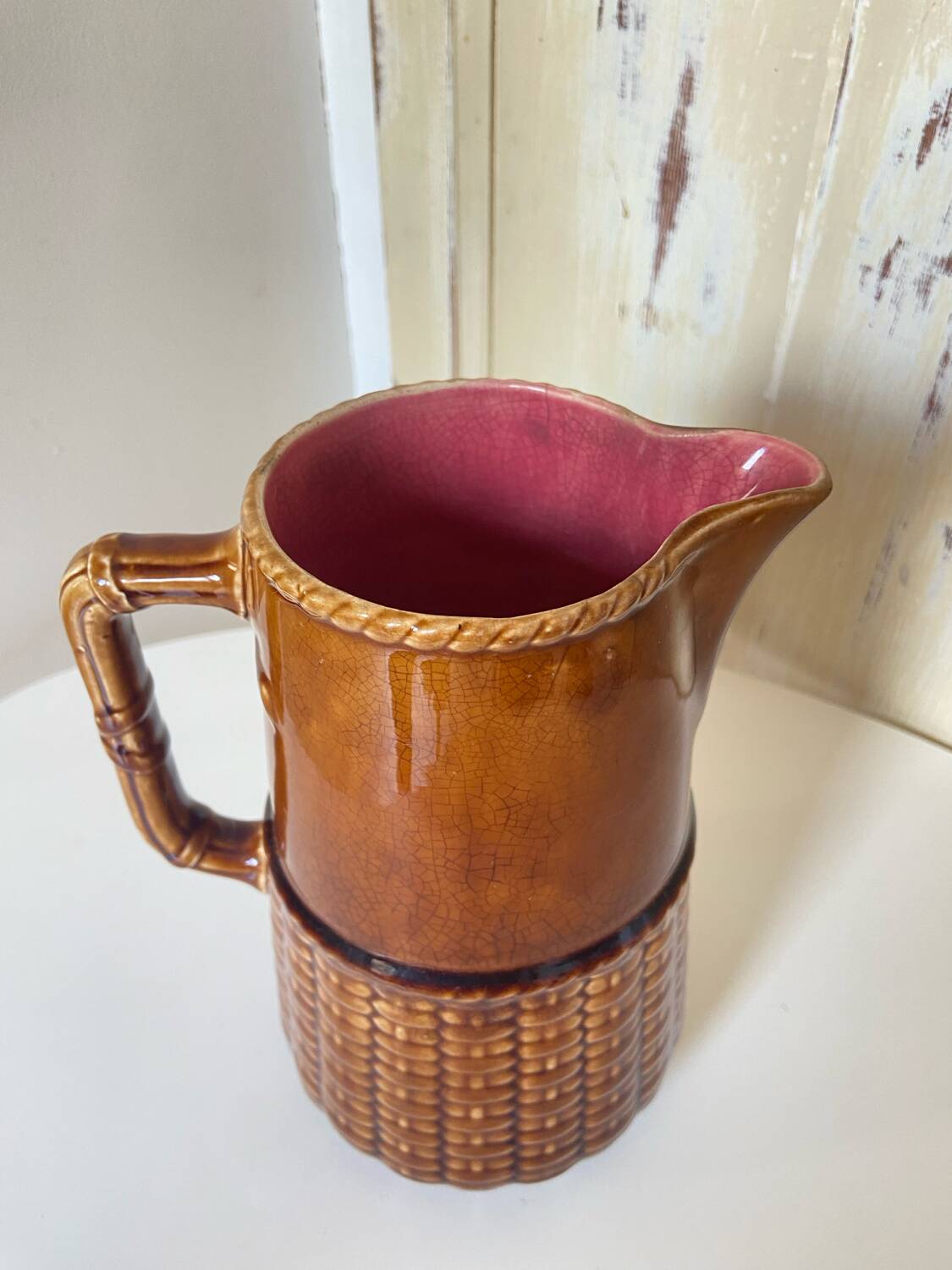 Antique vintage ceramic pitcher or jug from Sarreguemines, France. Brown with a pink interior, imitation basket.