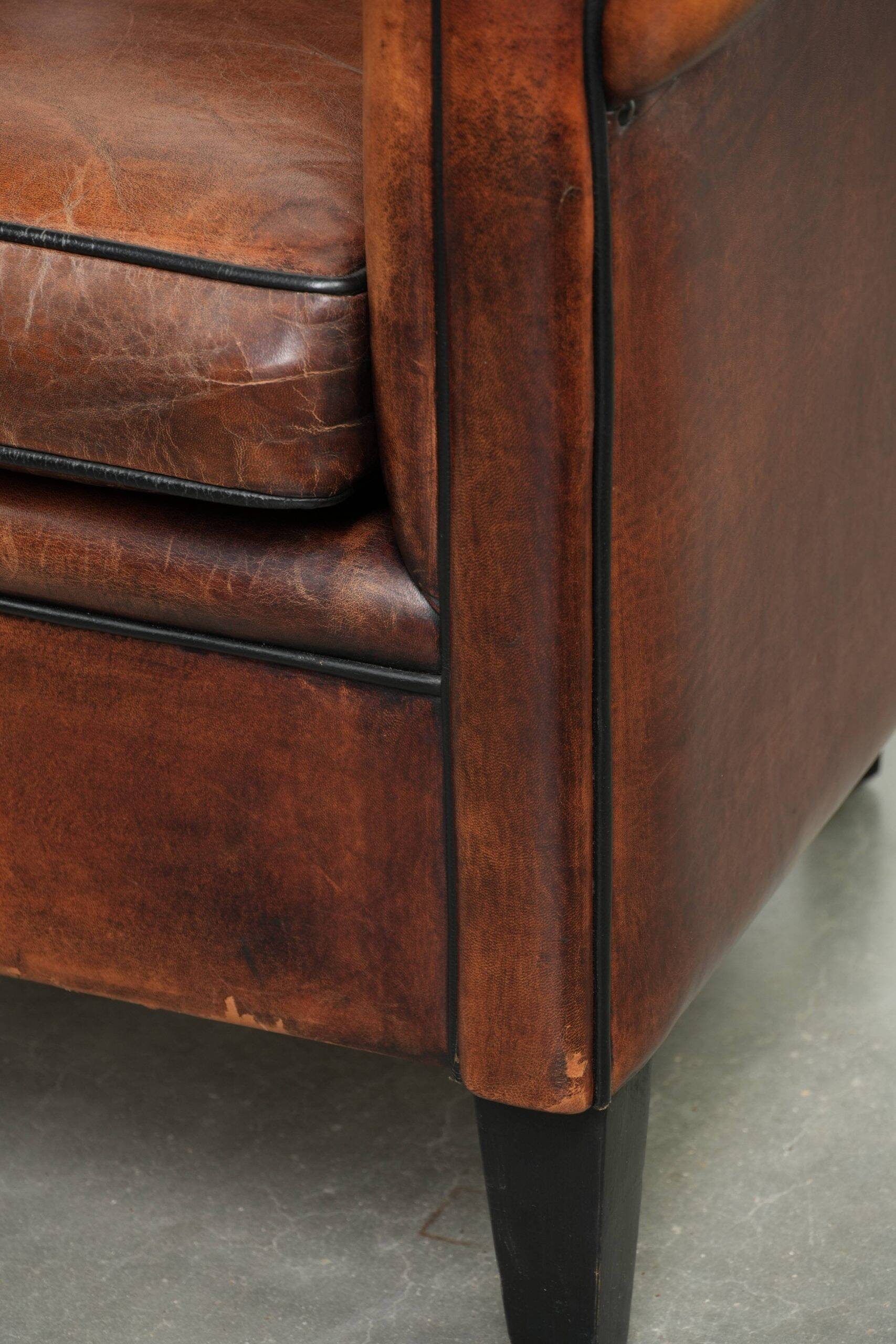 Sheepskin club armchair with deep warm colours and black piping