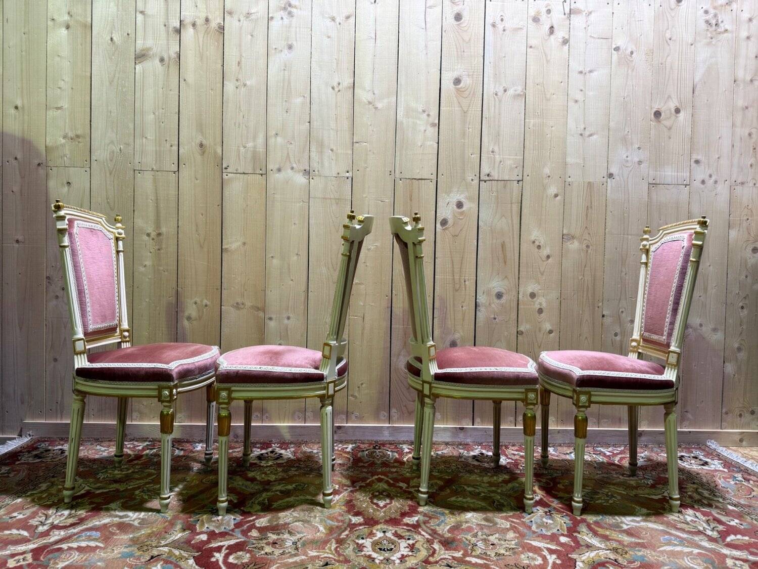 Louis XVI dining room table set with painted wood, gold accents, and pink velvet.
