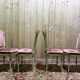 Louis XVI dining room table set with painted wood, gold accents, and pink velvet.