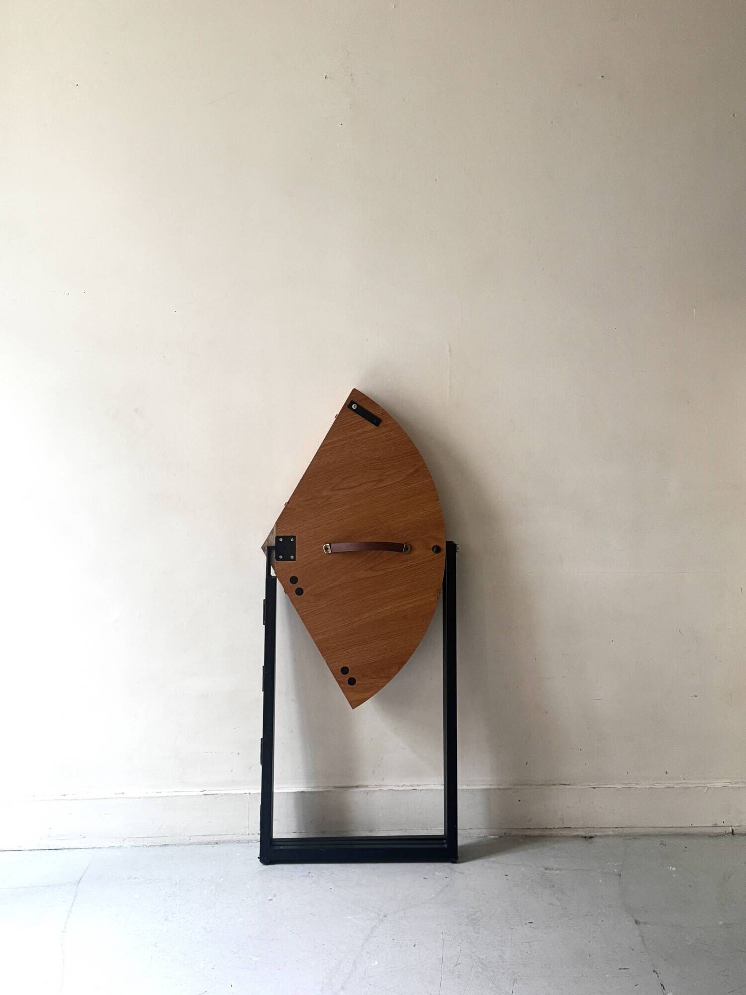 Modernist round folding dining table in wood and metal.