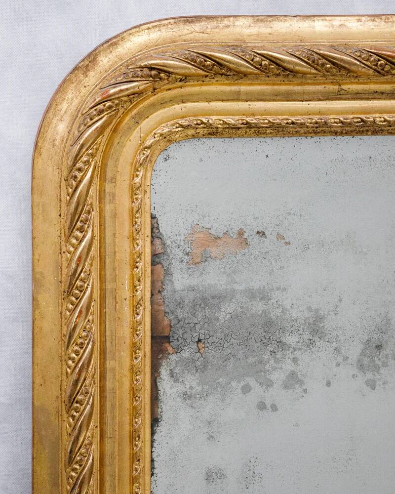 19th-century patinated mirror with a ribbon-style frame