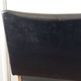 Chrome metal chairs and black faux leather upholstery in retro modernist style.