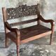 Small antique Indonesian bench in carved teak with plant and floral motifs.