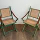 Paire de chaises safari pliantes façon faux-bambou patiné, dossiers et assises cannées et repose-bras en cuir