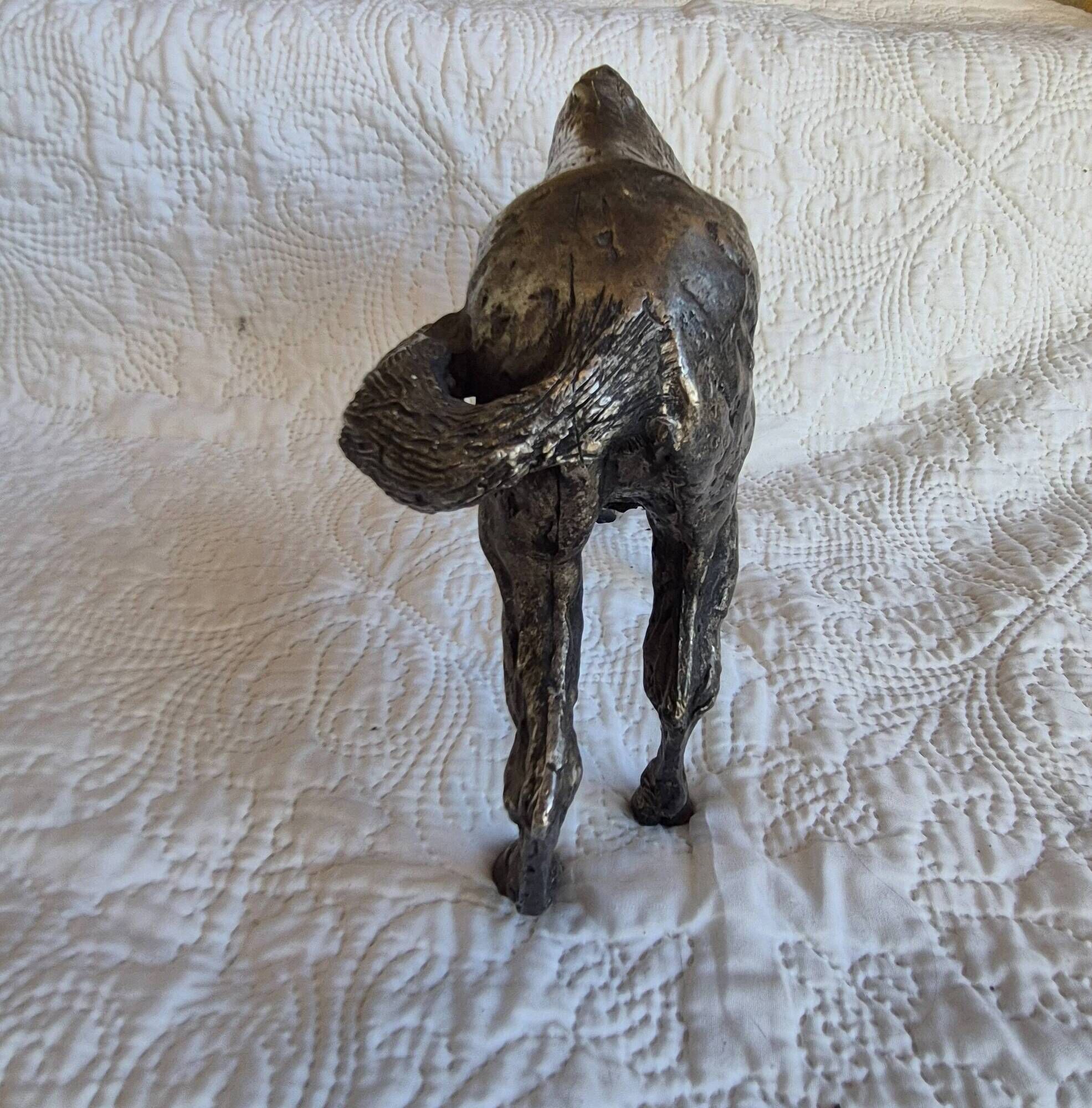 Sculpture of a grazing horse with a silver finish.