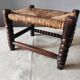 Antique wooden turned spool footrest with straw.