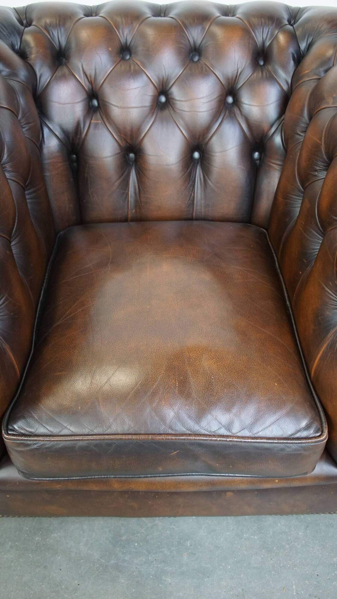 Cowhide English Chesterfield armchair with ball legs and timeless finish