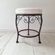 Black iron stool/pouf with its boucle fabric cushion.