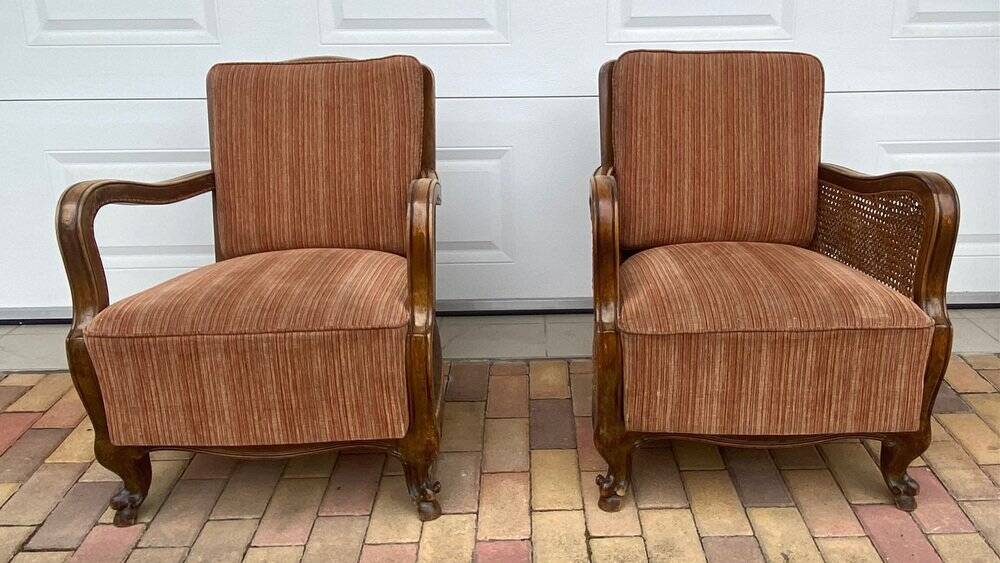 Pair of 1920s brown armchairs in carved wood and fabric, with caning detail.