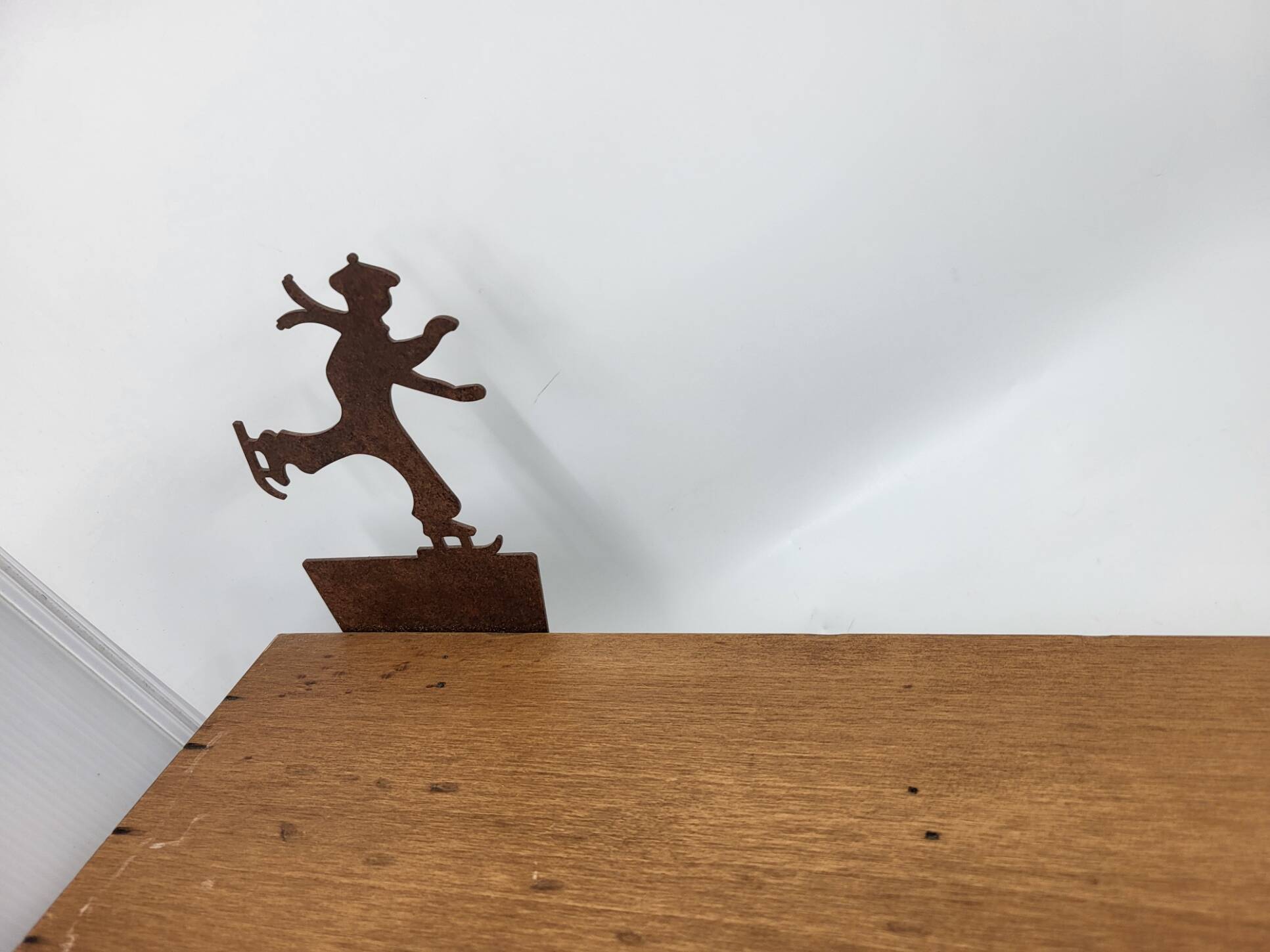 Wall shelf in wood and metal with a decoration of ice skaters.