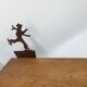 Wall shelf in wood and metal with a decoration of ice skaters.