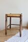 Antique square wooden stool with a woven straw seat.