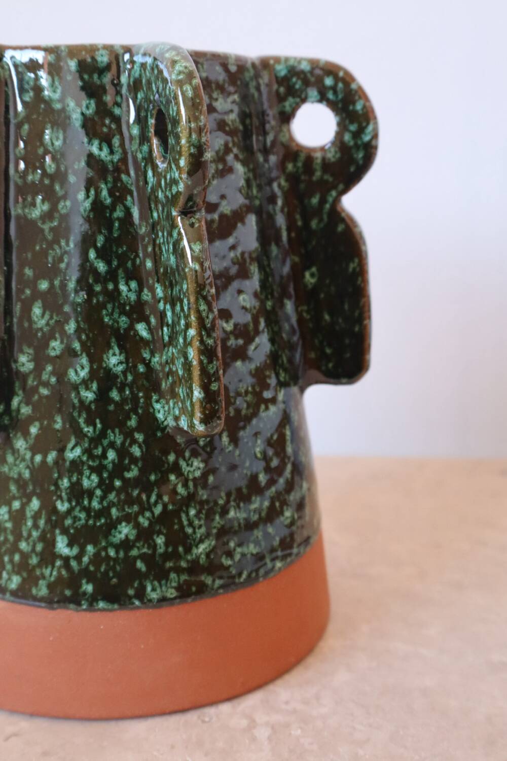 Sculptural ceramic vase with dark green glaze and shimmering highlights