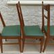 6 modern chairs with banded backs and green faux leather seats.