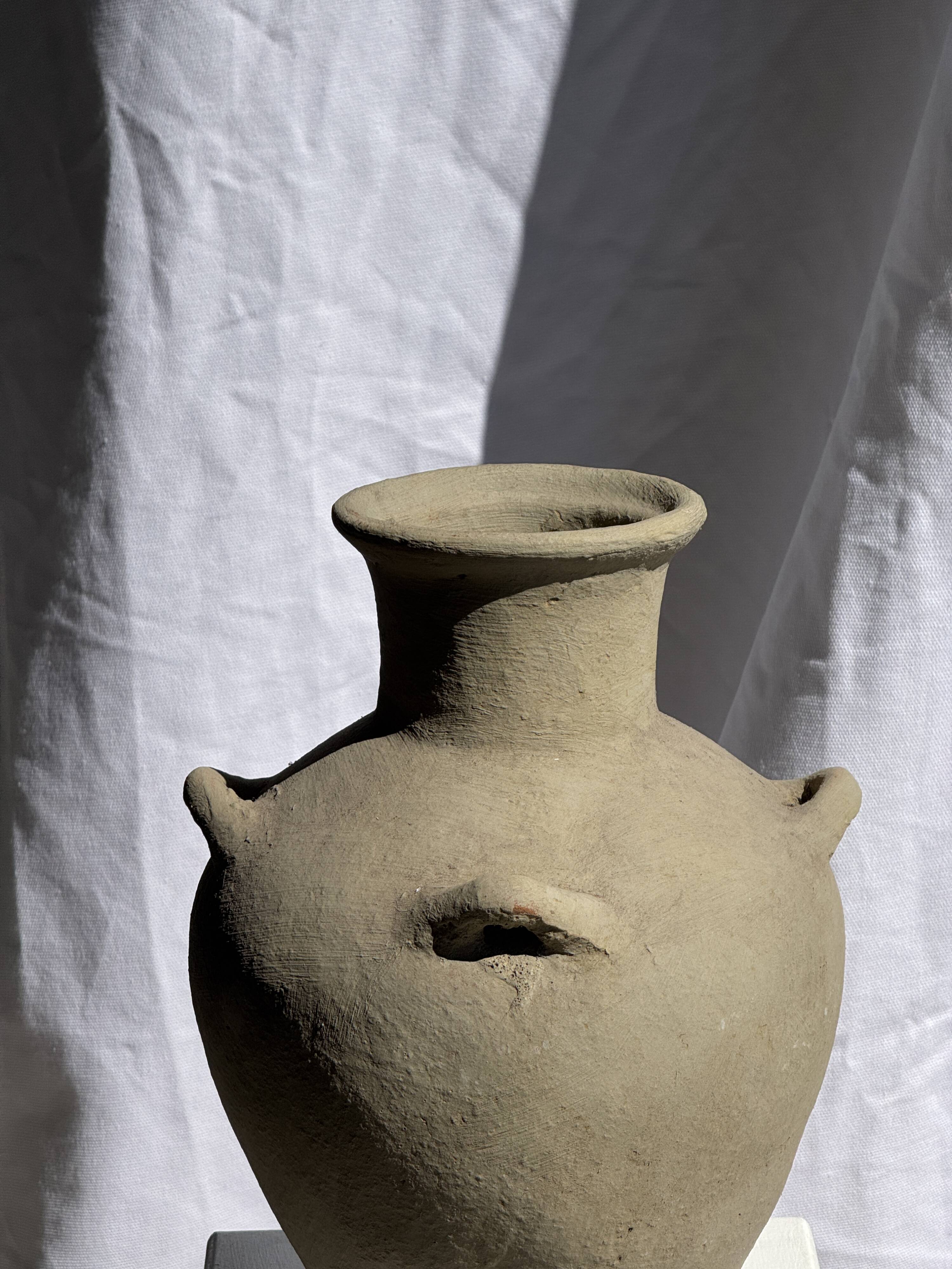Light beige-grey Indonesian terracotta vase with 4 small handles and a high neck.