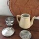 Old tea pot or coffee maker in faience cream with filter.