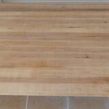 Large natural wood table with rectangular top supported by legs