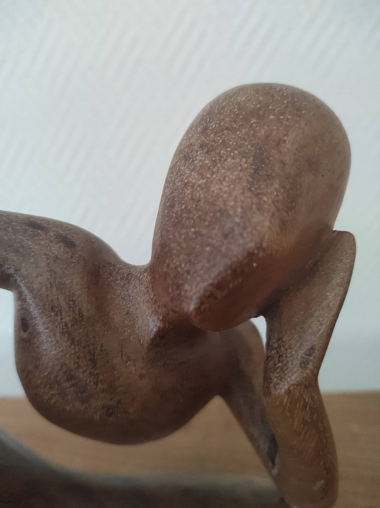 Wooden sculpted statuette of a woman in a pensive pose.