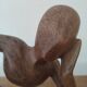 Wooden sculpted statuette of a woman in a pensive pose.