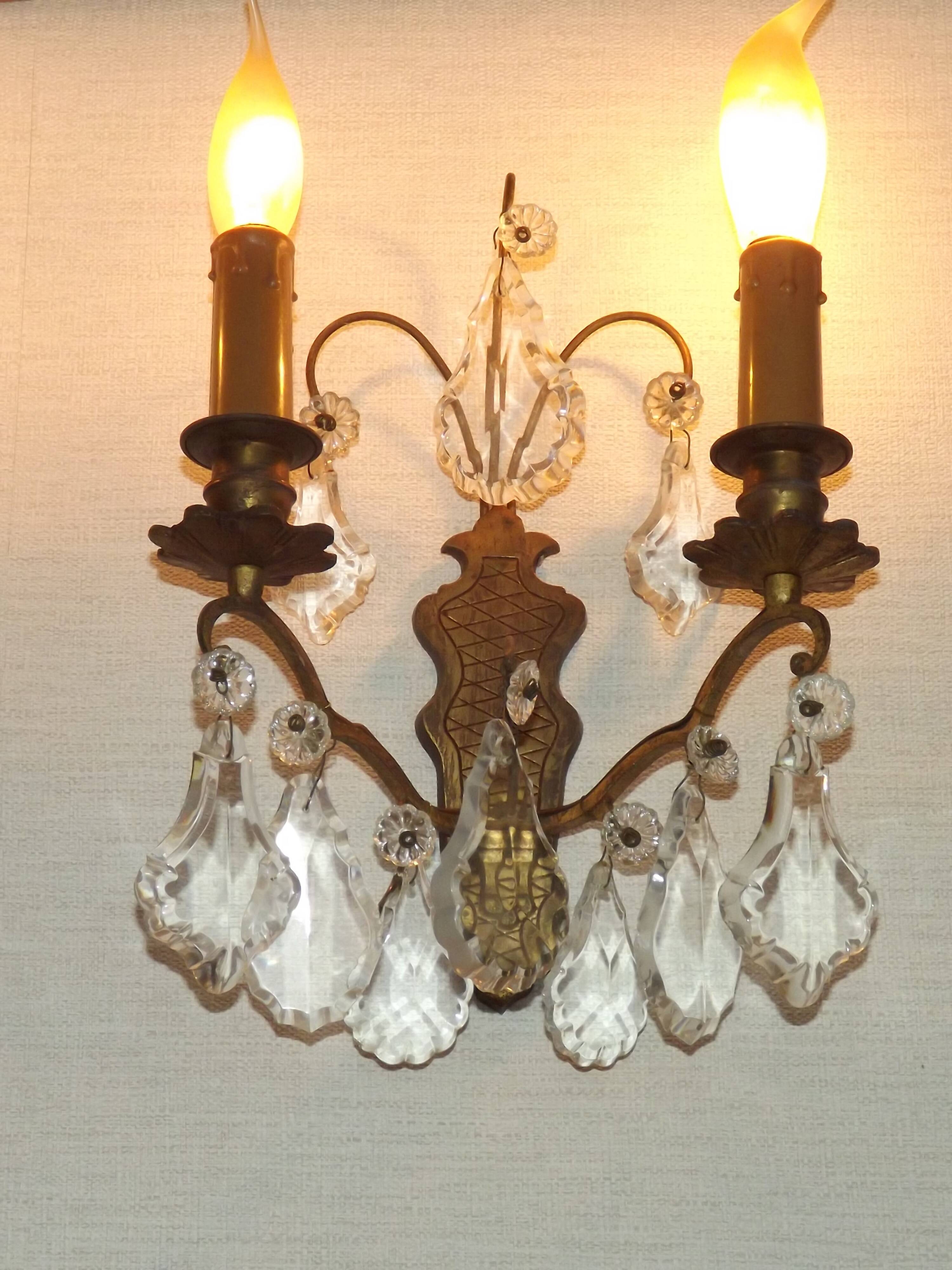 Pair of French antique brass double wall lights with assorted crystals.