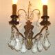 Pair of French antique brass double wall lights with assorted crystals.