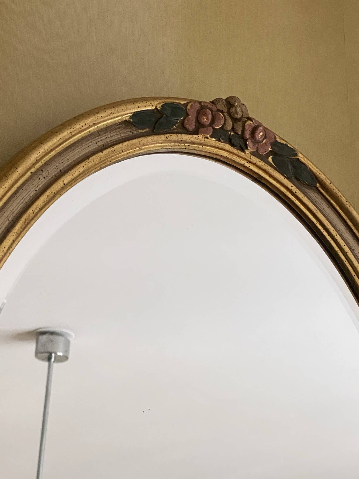 Oval wooden frame with floral decoration in gold.