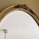 Oval wooden frame with floral decoration in gold.
