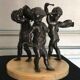 Three musician angels, bronze sculptures on a marble base.