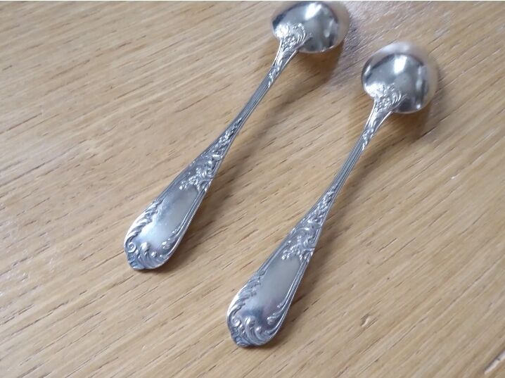 2 small white metal spoons