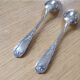 2 small white metal spoons
