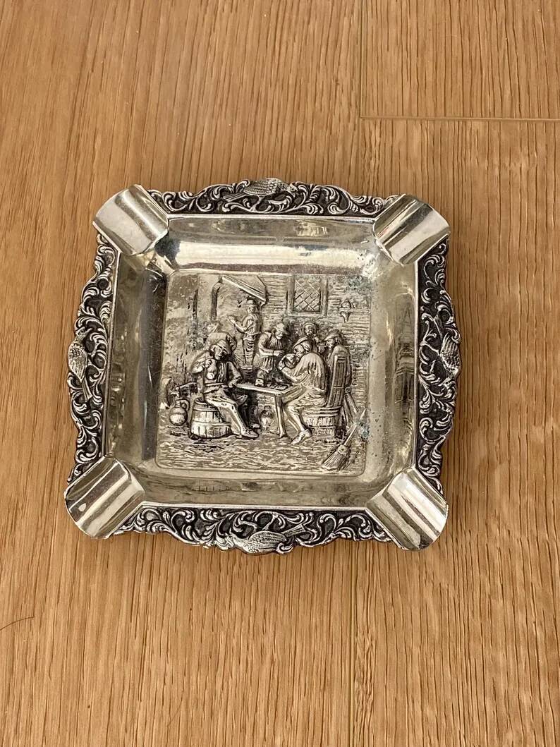 Antique silver-plated ashtray, decorated with repoussé scenes of a tavern, pin tray.