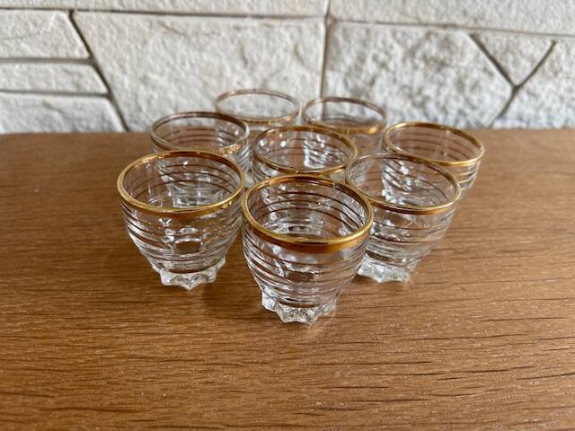 Suite of eight liqueur glasses in white glass and gold highlights. Circa 1970