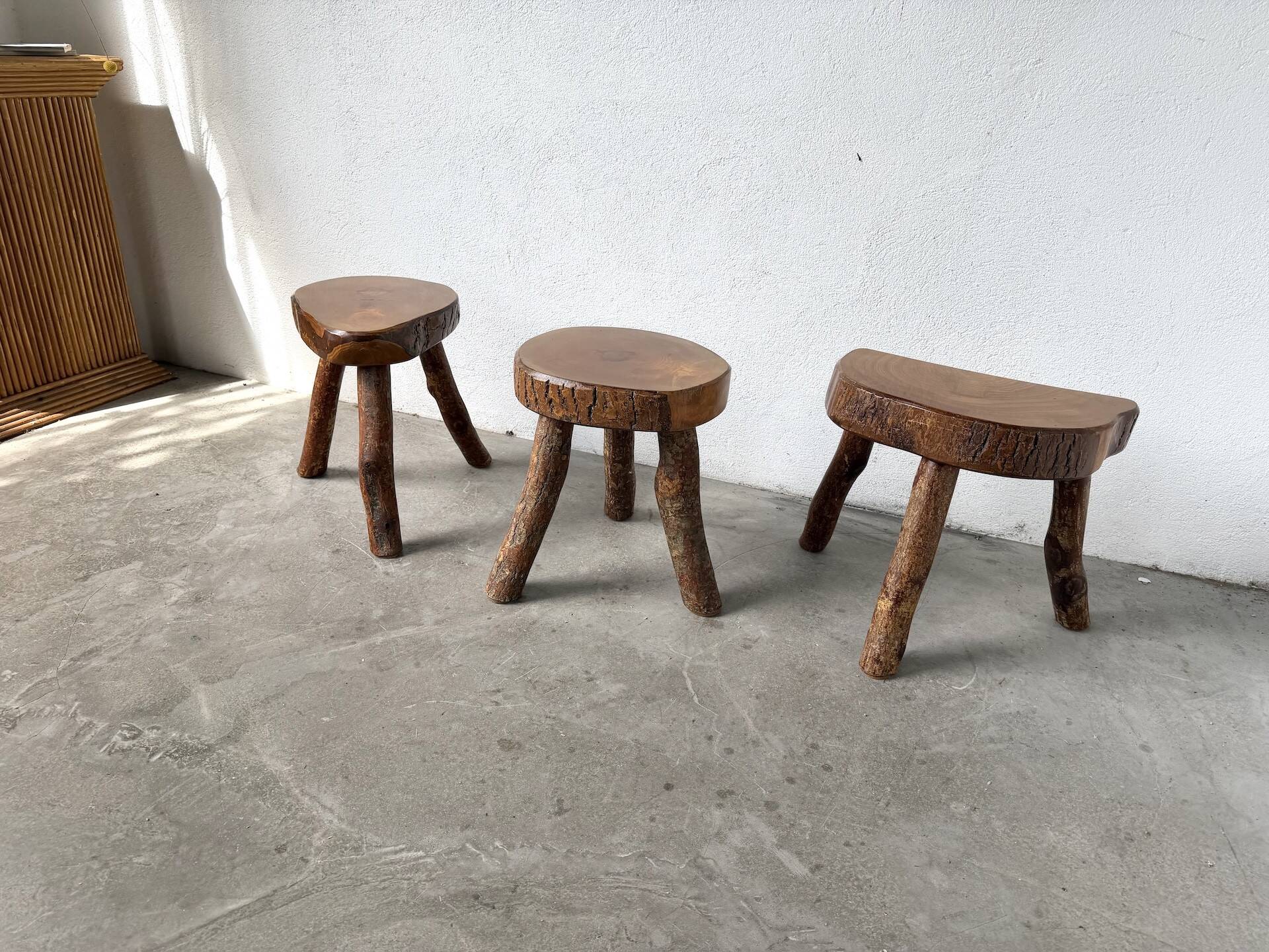 Set of three rustic solid wood tripod stools.