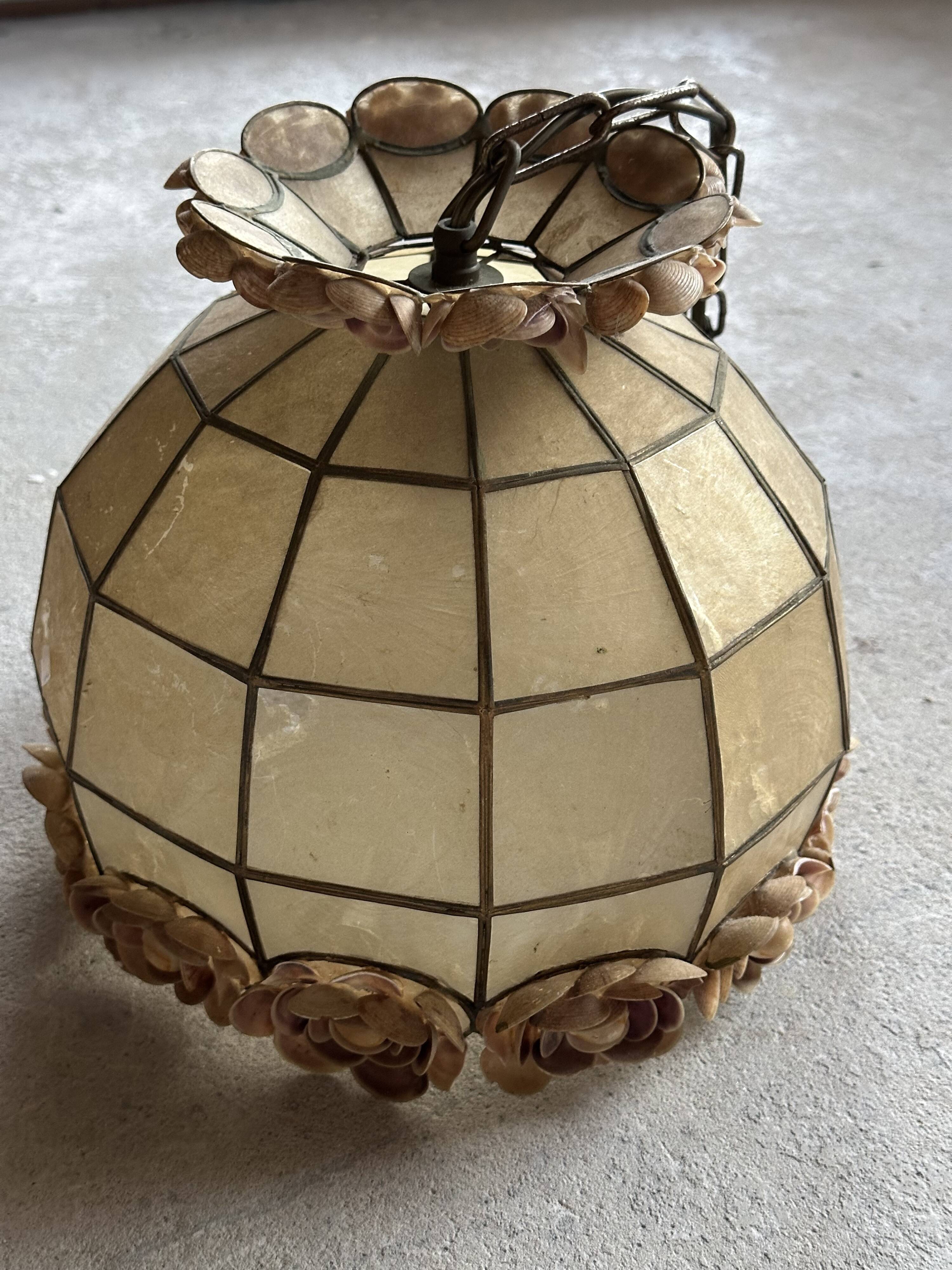 Vintage pendant light with a pearlescent shade and floral decoration.