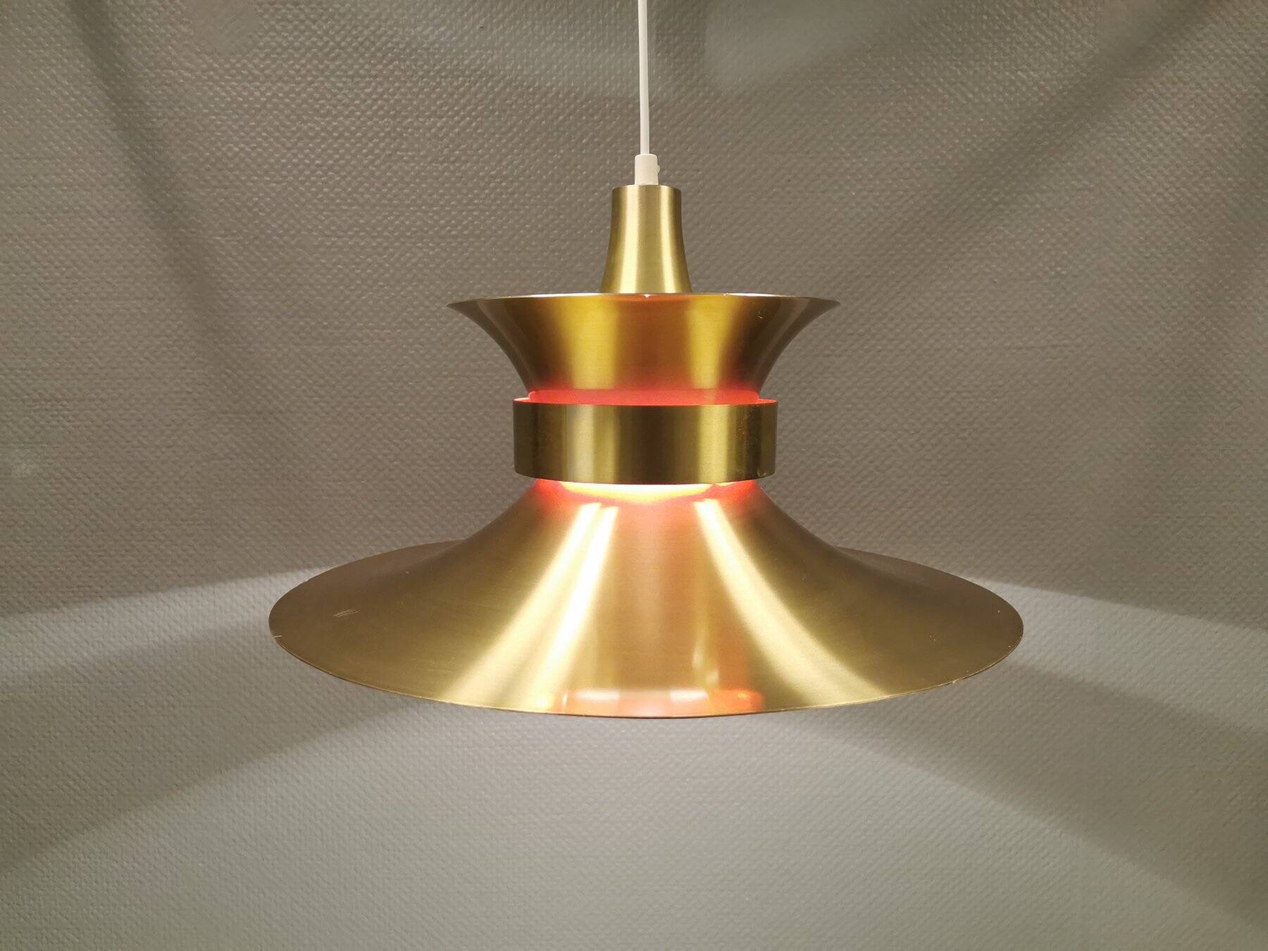 Large hanging lamp, made of brass-coloured aluminium with red and white contrast lacquer inside.